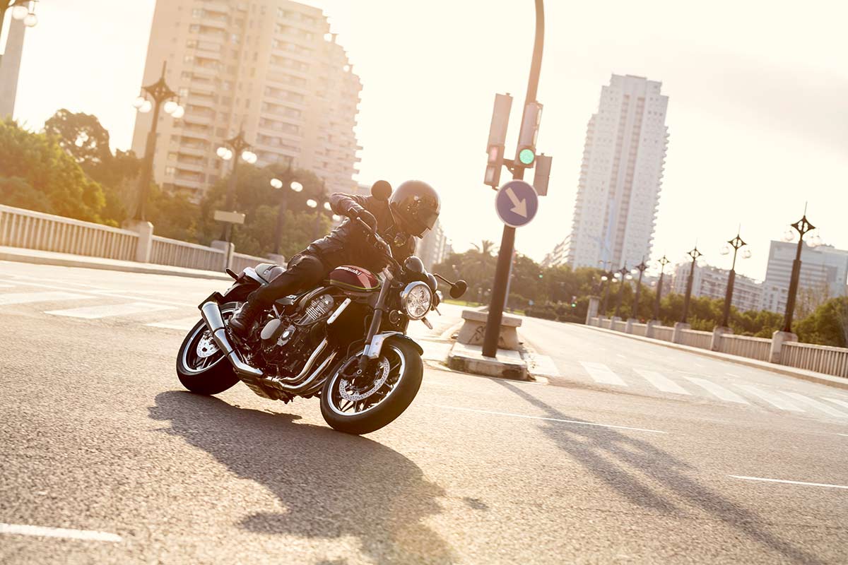 Three-quarter front angle of a person riding a motorcycle on a paved road.