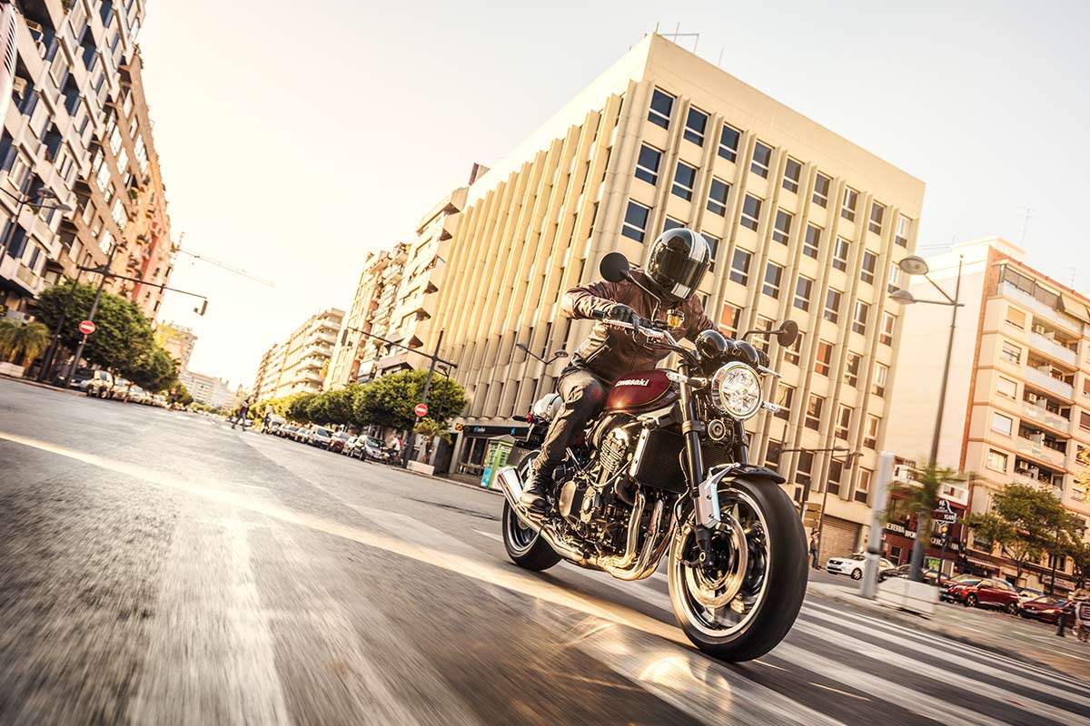 Three-quarter front angle of a person riding a motorcycle in a city.