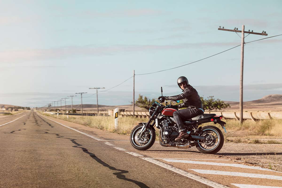 Side angle of a person on a motorcycle by a highway.