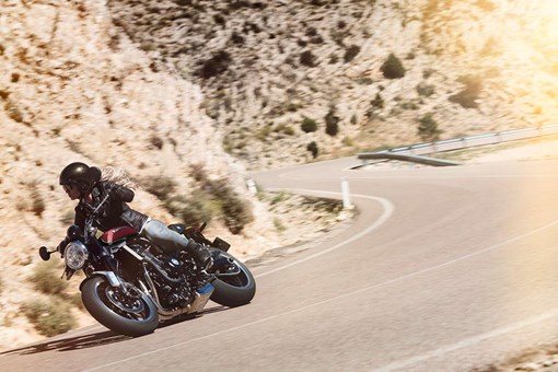 Three-quarter front angle of a person riding a motorcycle on a highway. opens in a new window