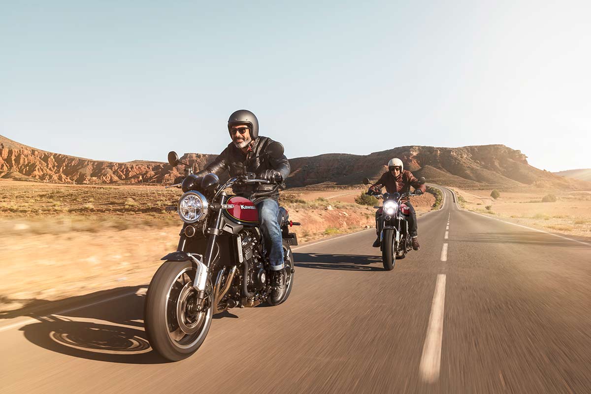Three-quarter front angle of two people riding motorcycles on a highway.
