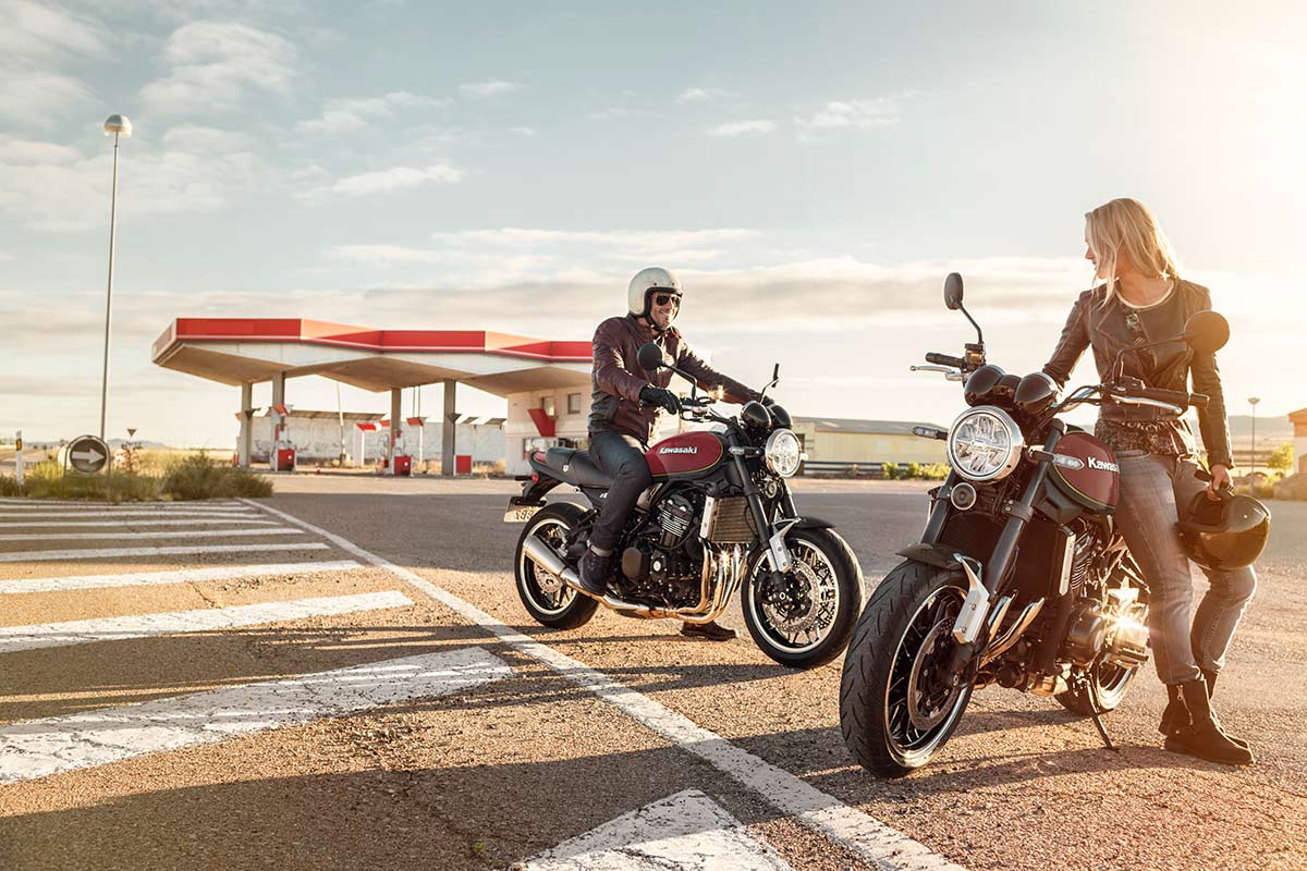 Three-quarter front angle of two motorcycles at a gas station.