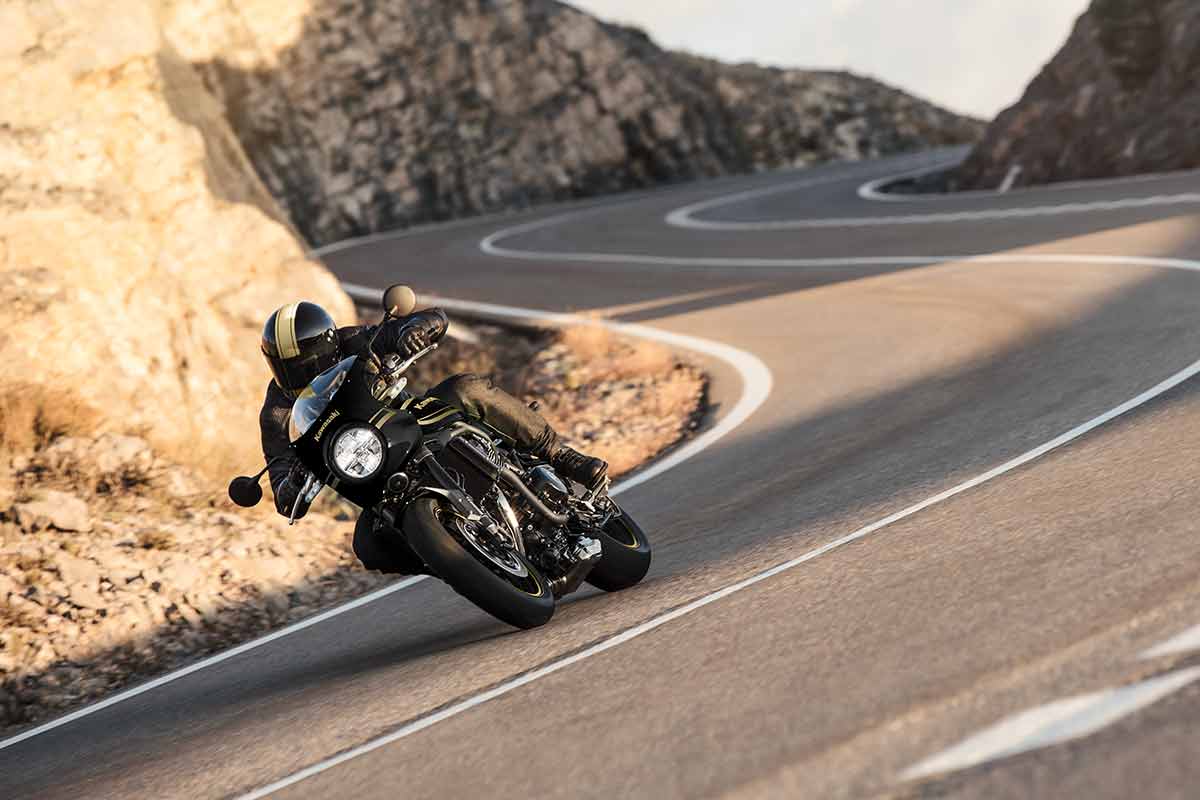 Three-quarter rear angle of a person riding a motorcycle on a highway.
