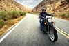  Front angle of a person riding a motorcycle through mountains.
