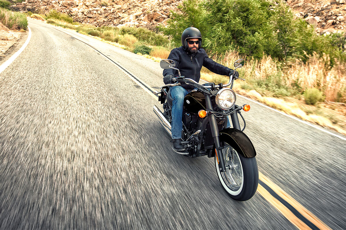 Three-quarter front angle of a person riding a motorcycle on a highway.