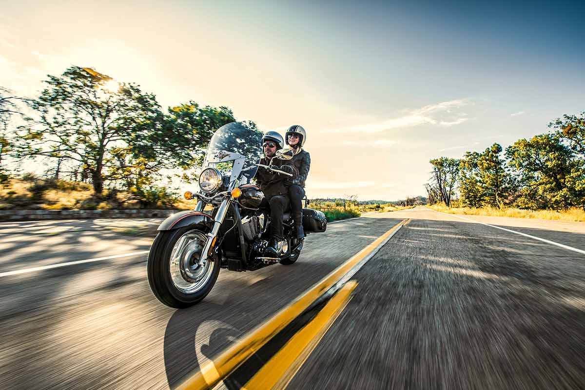 Three-quarter front angle of two people riding a motorcycle on a highway.