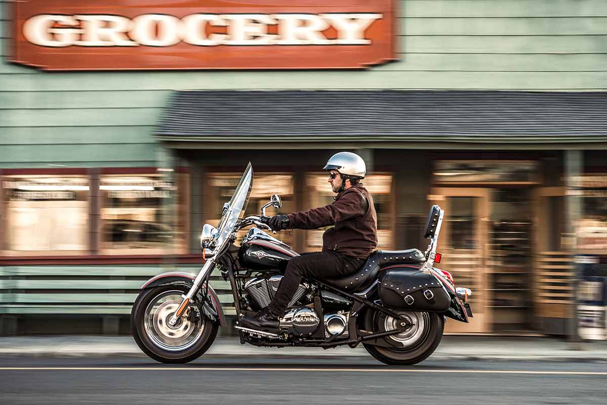 Side angle of a person riding a motorcycle on a paved road.