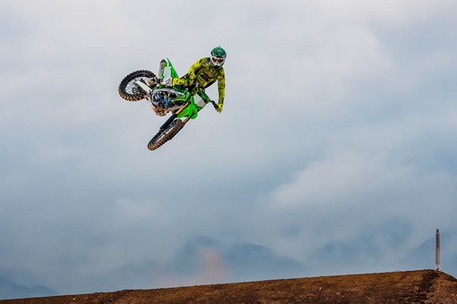 Three-quarter front angle of a person making a jump on a dirt track. opens in a new window