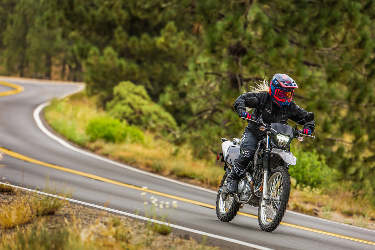 Three-quarter front angle of a person riding a motorcycle on a highway.
