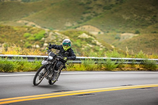 Three-quarter front angle of a person leaning into a turn on a motorcycle on a highway. opens in a new window