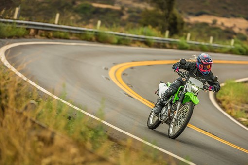 Three-quarter front angle of a person making a turn on a motorcycle on a highway. opens in a new window