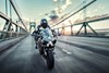 Front angle of a person riding a motorcycle on a bridge.