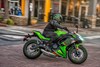 Profile angle of a lime green motorcycle riding in an urban city.
