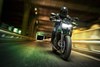 Front angle of a person riding a motorcycle at night in an urban city.