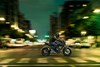 Side angle of a person riding a motorcycle in an urban city.