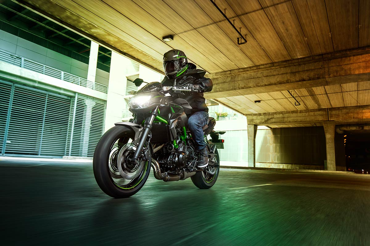 Three-quarter front angle of a person riding a motorcycle under an overpass.