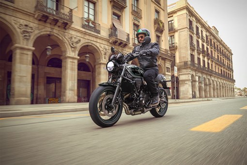 Three-quarter front angle of a person riding a motorcycle in downtown. opens in a new window