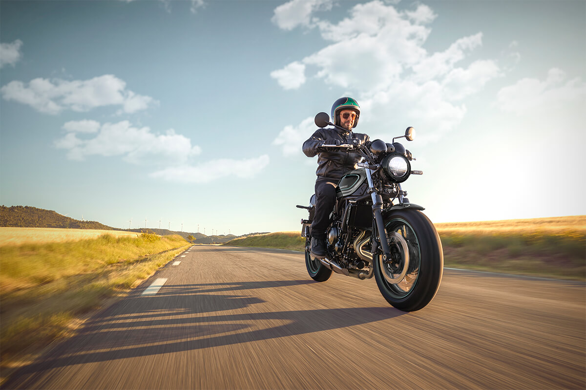 Three-quarter front angle of a person riding a motorcycle on a countryside highway.