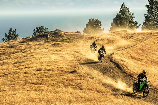 Front angle of three people riding motorcycles on a dirt trail. opens in a new window