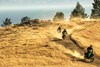 Front angle of three people riding motorcycles on a dirt trail.