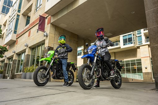 Three-quarter front angle of two people sitting on motorcycles in an urban city. opens in a new window