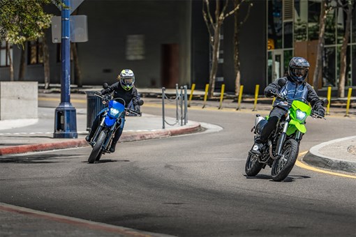 Three-quarter front angle of two motorcyclist making a turn in an urban city. opens in a new window