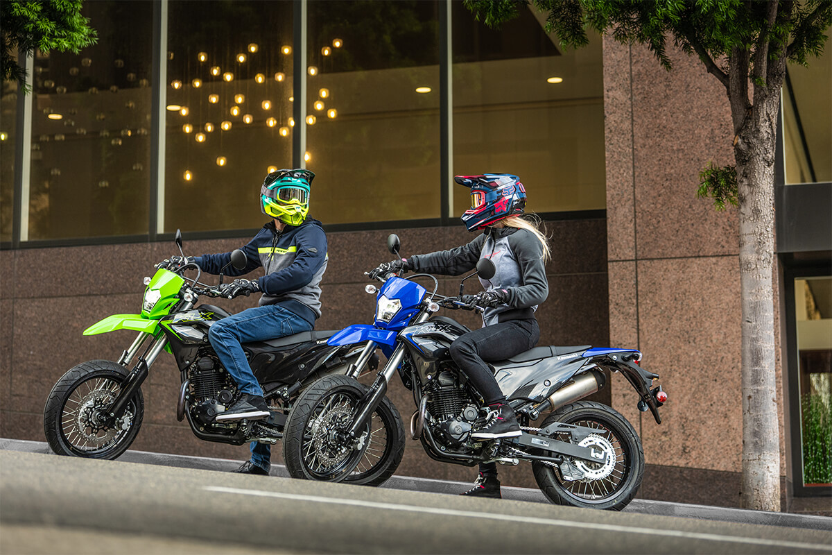 Side angle of two people sitting on idle motorcycles in an urban city.