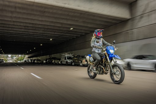 Three-quarter front angle of a person riding a motorcycle out of an overpass. opens in a new window