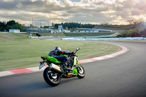 Three-quarter rear angle of a person riding a motorcycle on a track. opens in a new window