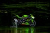 Side angle of a motorcycle staged in a green and black garage background.