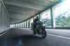 Three-quarter front angle of a person riding a motorcycle under an overpass.