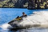 Side angle of a person making a turn on a personal watercraft on the water.
