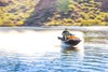 Three-quarter front angle of a person on a personal watercraft on the water with a blurred background.