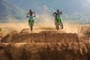 Front angle of two riders riding a motorcycle through the whoops on a dirt track.
