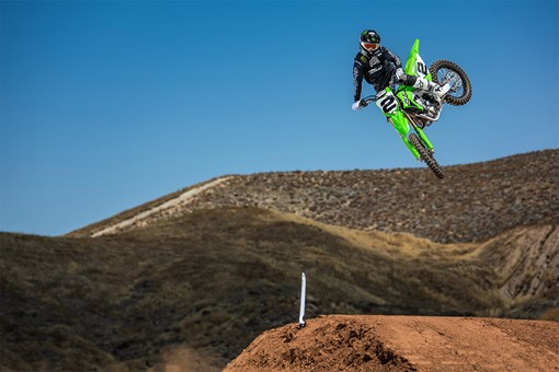 Three-quarter front angle of a person making a jump on a motorcycle off-road. opens in a new window