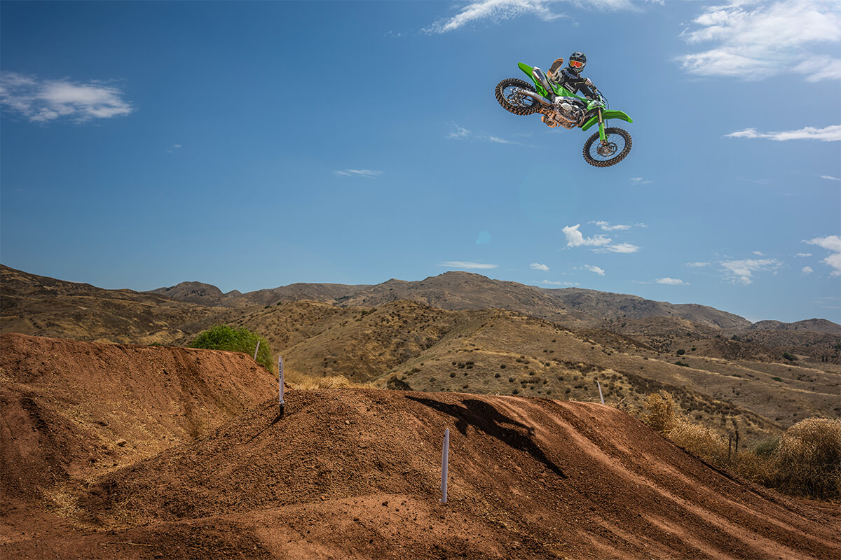 Side angle of a person mid air on a motorcycle off-road.