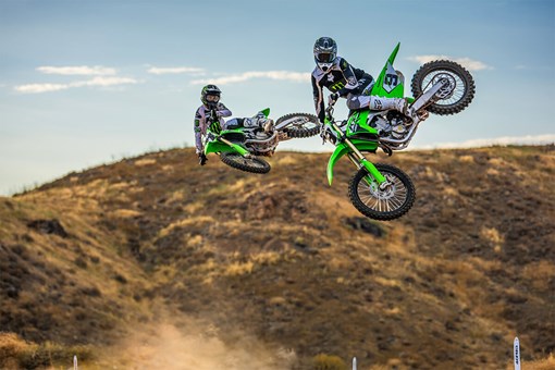 Front angle of two riders whipping their bikes mid air off-road. opens in a new window