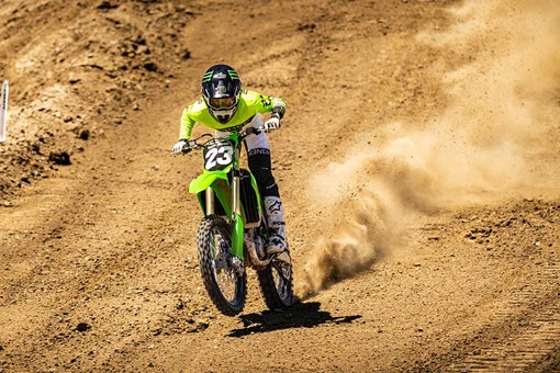 Front angle of a person doing a wheelie on a motorcycle on a track. opens in a new window