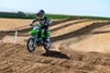 Three-quarter front angle of a child riding a motorcycle through the whoops on a track.