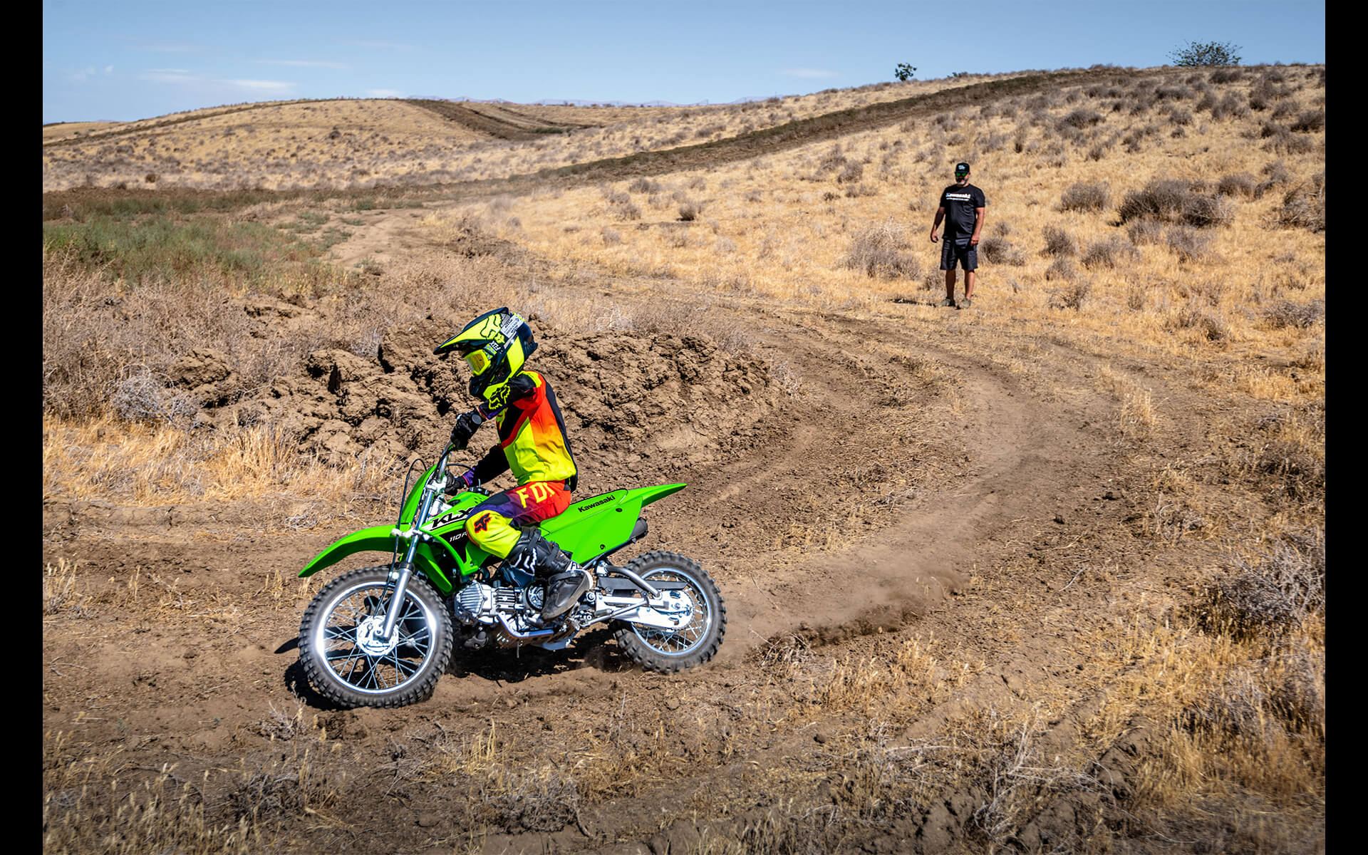 Three-quarter front angle of a person riding a motorcycle off-road around a corner.