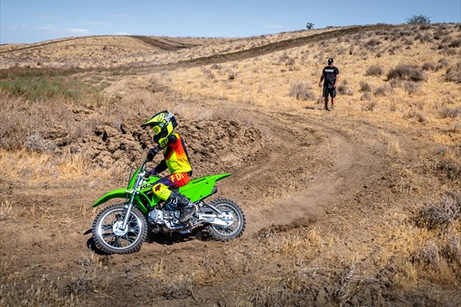 Three-quarter front angle of a person riding a motorcycle off-road around a corner. opens in a new window