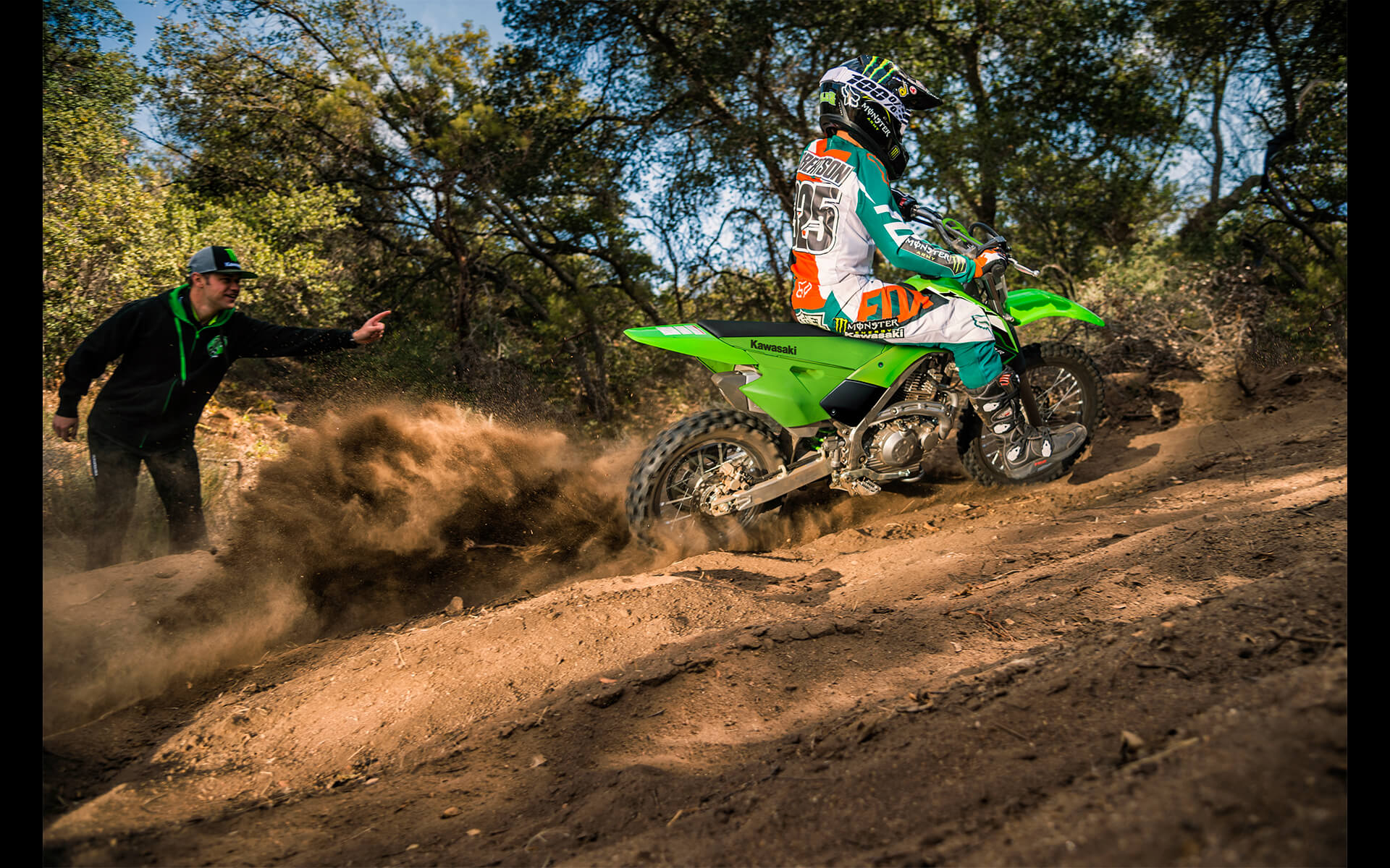 Three-quarter rear angle of a person riding a motorcycle off-road.