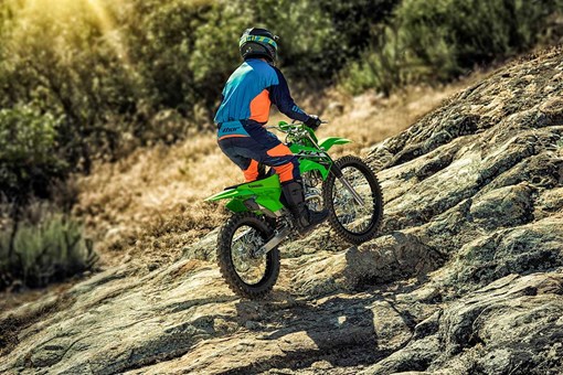 Three-quarter rear angle of a person riding a motorcycle off-road. opens in a new window