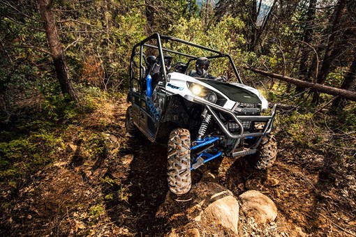 Front angle of a person and passengers driving a side x side off-road up hill. opens in a new window