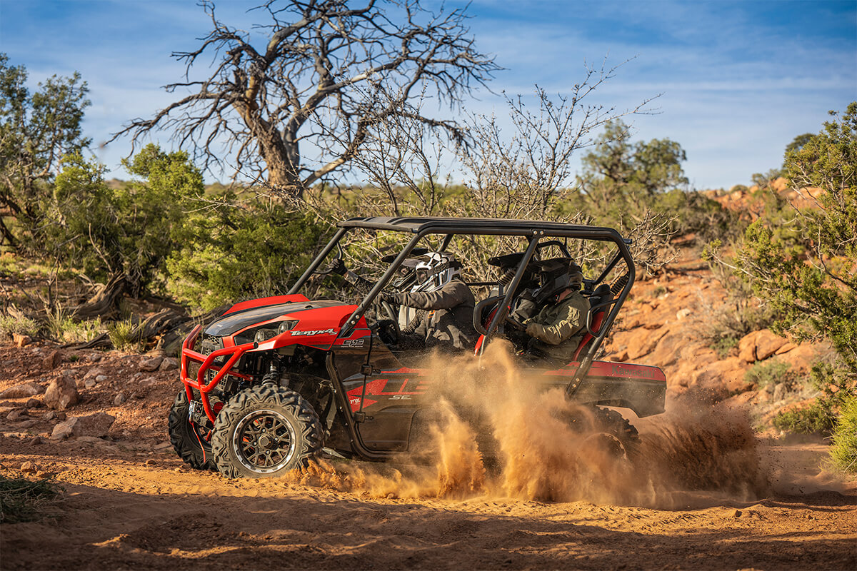 Side angle of a person and passengers driving a side x side off-road.