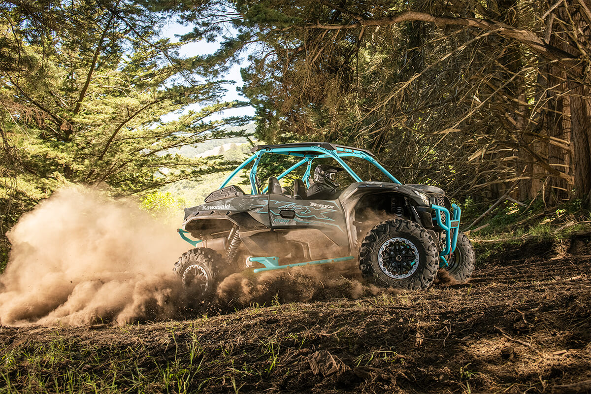 Side angle of a person driving a side x side off-road through trees.