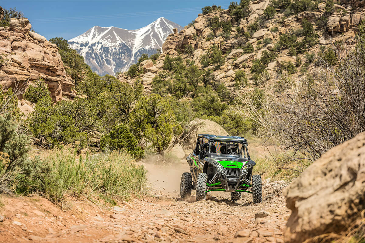 Front angle of a person and passengers driving a side x side off-road.