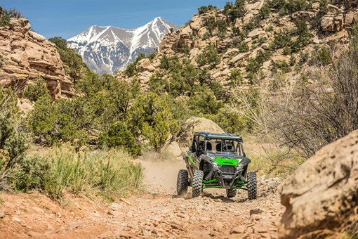 Front angle of a person and passengers driving a side x side off-road. opens in a new window