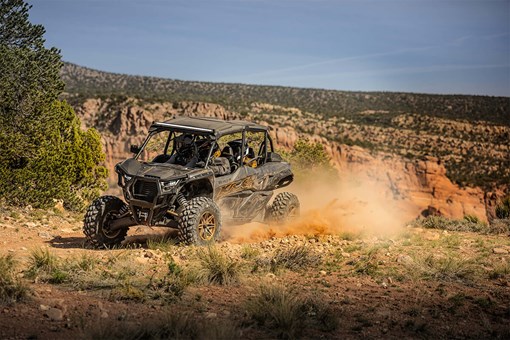 Three-quarter front angle of a person driving a side x side off-road. opens in a new window