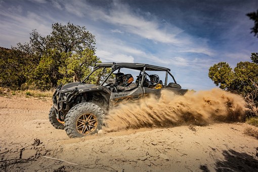 Side angle of a person and passengers driving a side x side off-road. opens in a new window